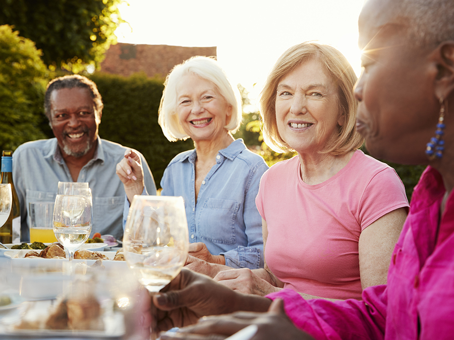 Group of friends and neighbors having a summer dinner party outdoors.